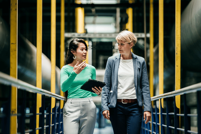 Business professionals discussing in industrial factory setting.